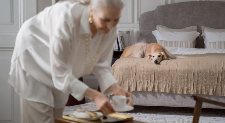 A woman holding a cup of tea next to her dog.